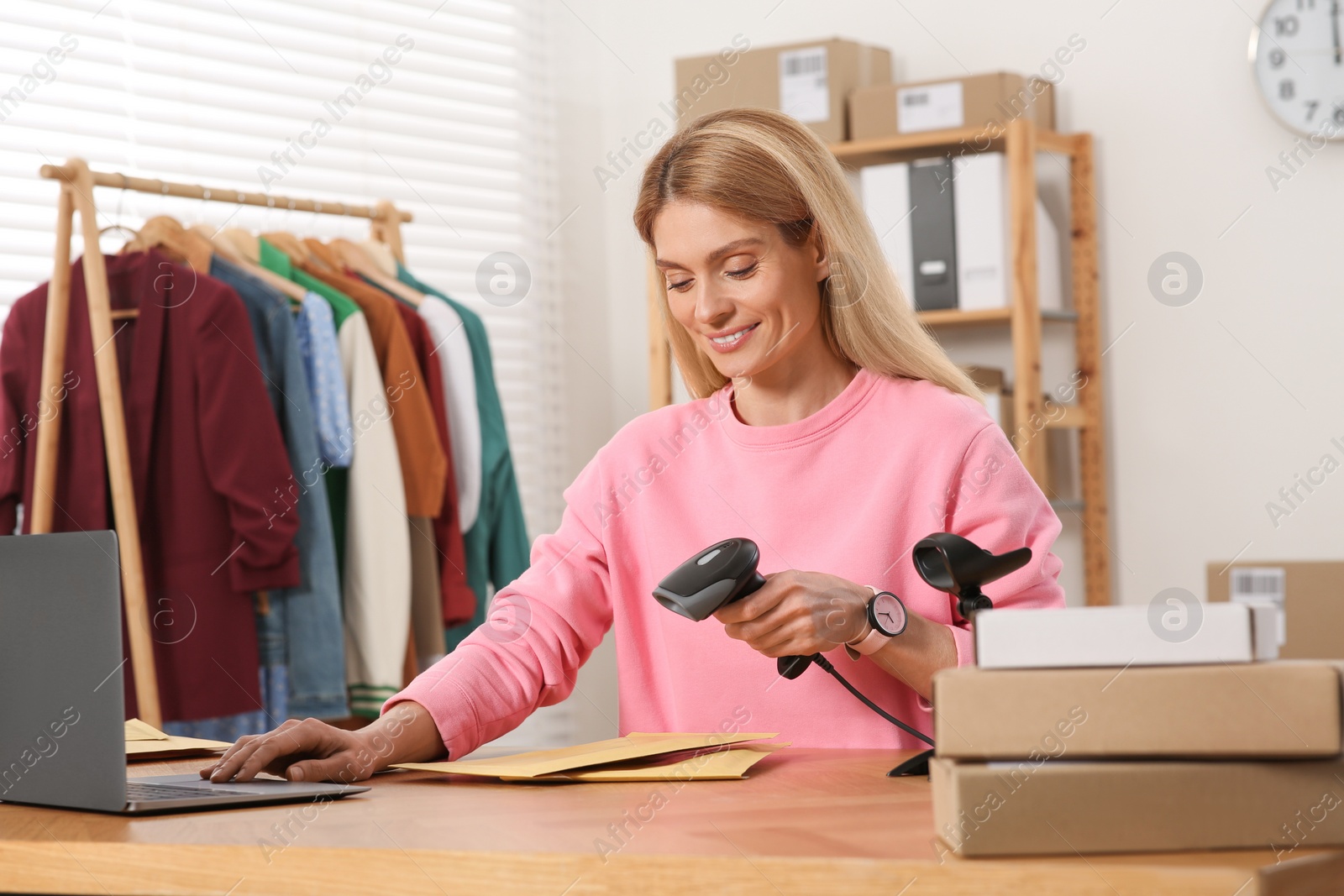 Photo of Seller with scanner reading parcel barcode in office. Online store