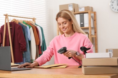 Photo of Seller with scanner reading parcel barcode in office. Online store