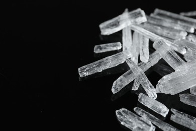 Menthol crystals on black background, closeup. Space for text
