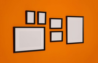 Empty frames hanging on orange wall. Mockup for design