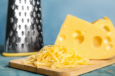 Photo of Tasty grated cheese on blue wooden table, closeup