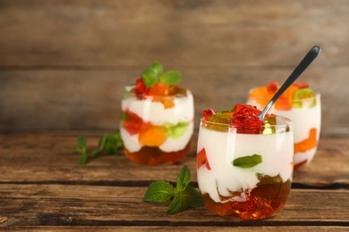 Photo of Delicious broken glass jelly dessert on wooden table, space for text