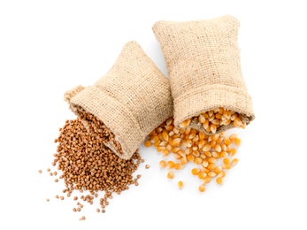 Bags with buckwheat and corn kernels on white background. Healthy grains and cereals