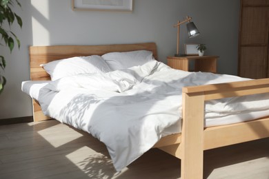 Photo of Large comfortable bed with soft pillows and blanket indoors