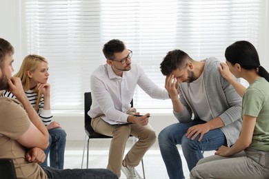 Photo of Psychotherapist working with group of drug addicted people at therapy session indoors