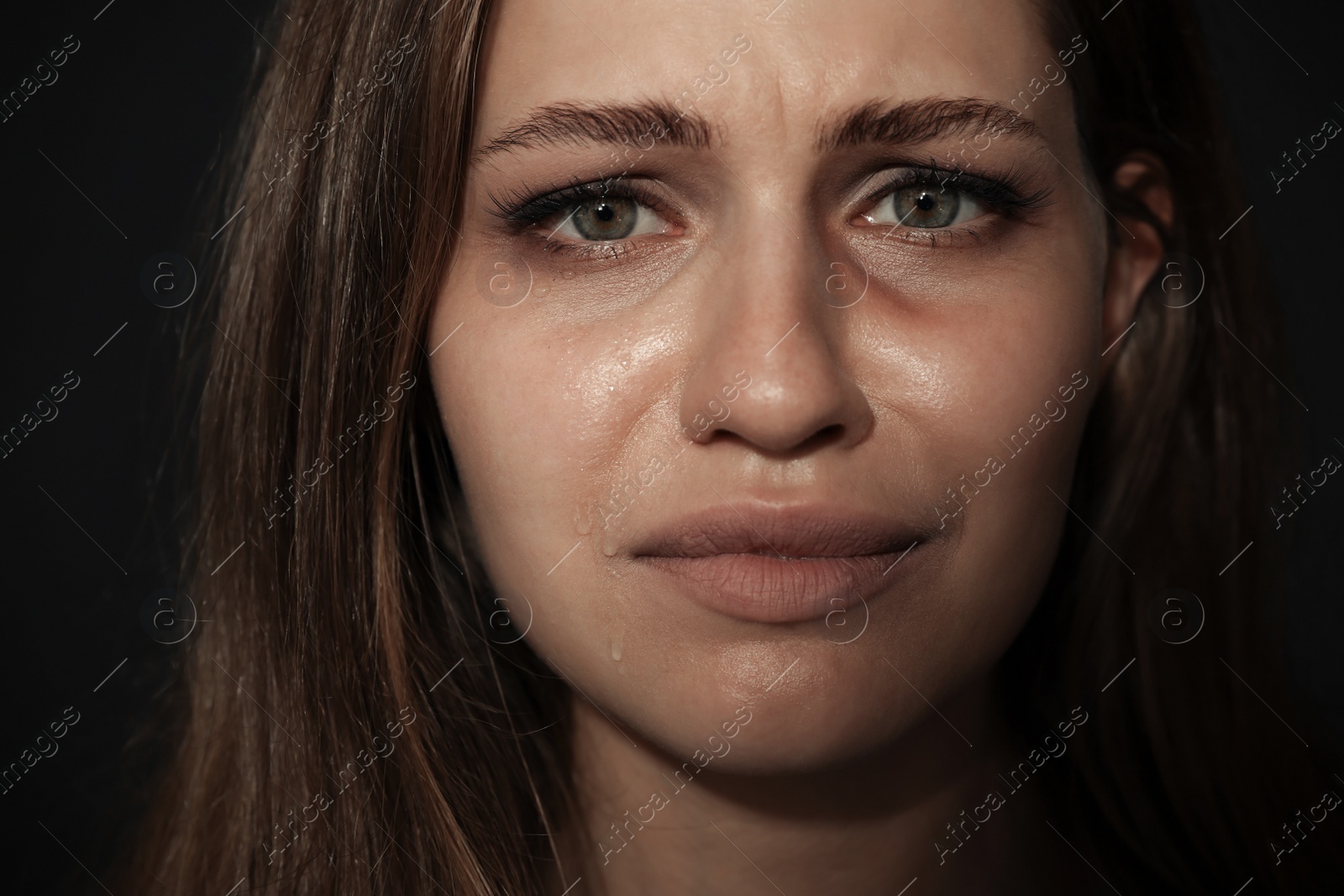Photo of Crying young woman on dark background. Stop violence