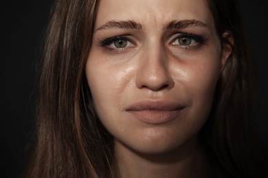 Photo of Crying young woman on dark background. Stop violence