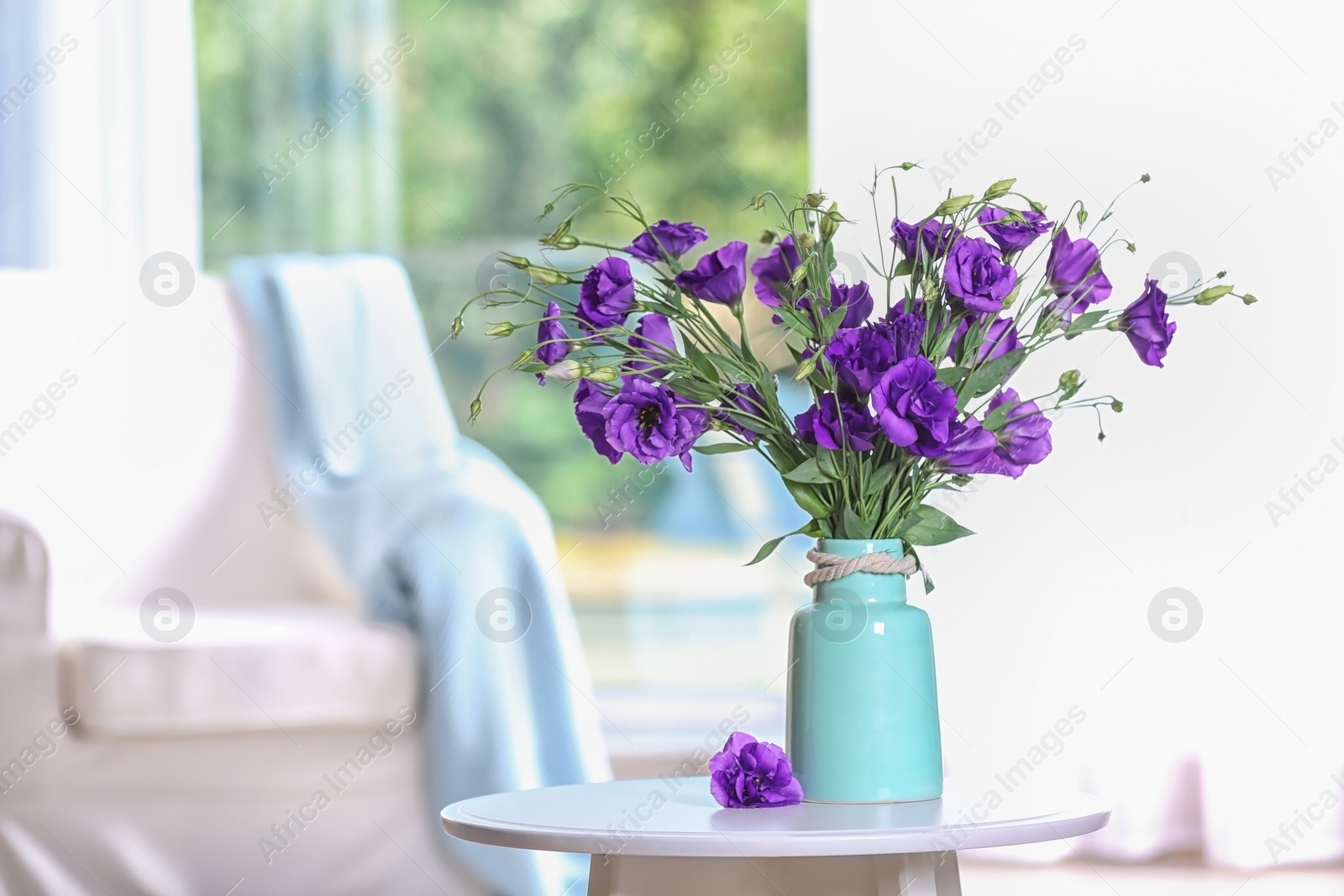 Photo of Beautiful bouquet of purple eustoma flowers in vase and space for text on blurred background