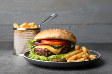 Delicious burger and french fries served on grey table