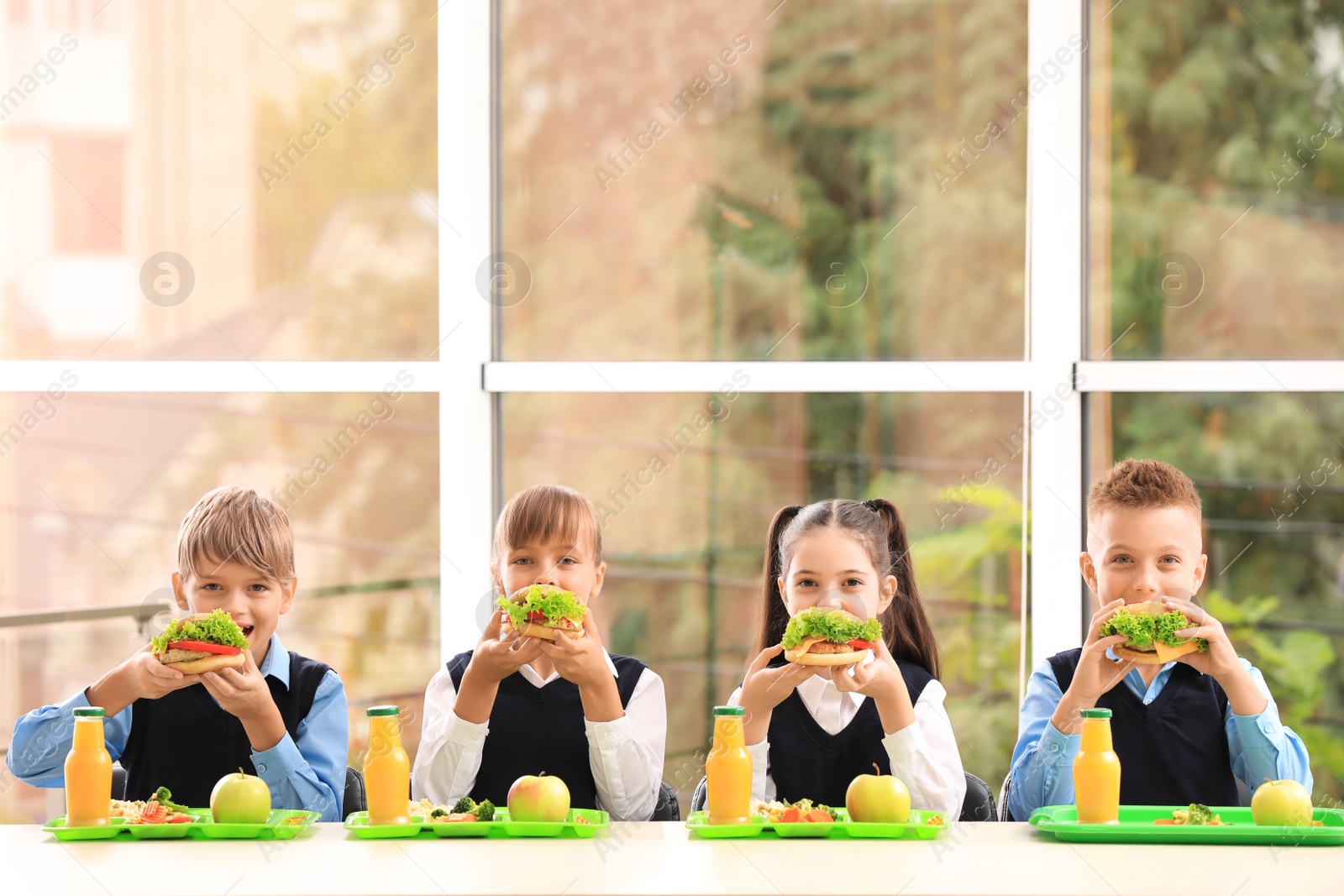 Photo of Happy children eating healthy food for lunch in school canteen