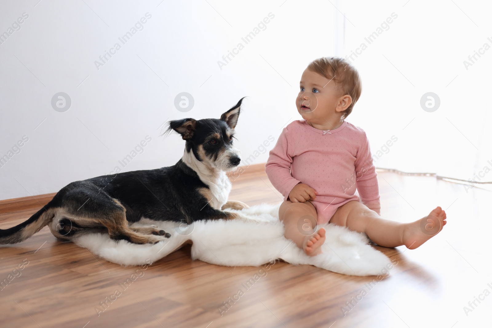 Photo of Adorable baby and cute dog on faux fur rug indoors