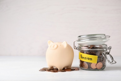 Piggy bank and jar of coins with word PENSION on table. Space for text