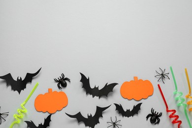 Photo of Flat lay composition with paper bats, spiders, pumpkins and cocktail straws on light grey background, space for text. Halloween decor