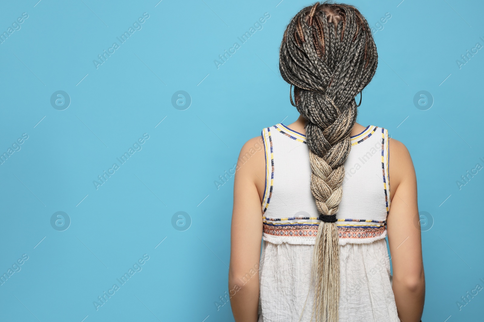 Photo of Woman with long african braids on blue background, back view. Space for text