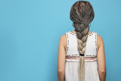 Photo of Woman with long african braids on blue background, back view. Space for text