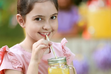 Cute little girl drinking natural lemonade in park, closeup with space for text. Summer refreshing beverage