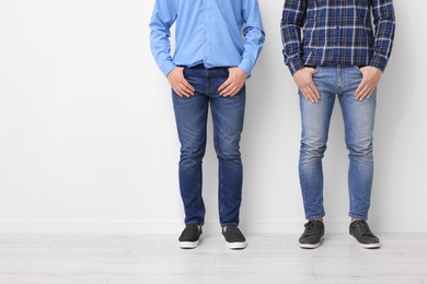 Photo of Men in stylish jeans near white wall indoors, closeup. Space for text