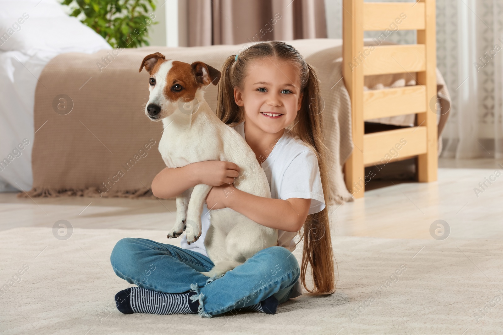 Photo of Cute girl hugging her dog on floor at home. Adorable pet