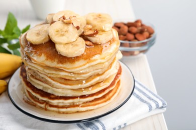 Photo of Tasty pancakes with sliced banana served on white wooden table. Space for text