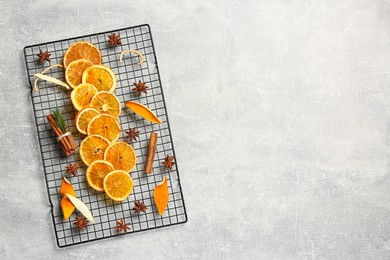 Photo of Flat lay composition with dry orange slices, anise stars and cinnamon sticks on light grey table. Space for text
