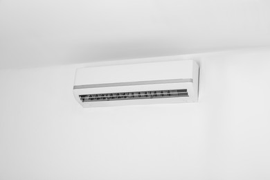 Modern air conditioner on white wall indoors. Space for text