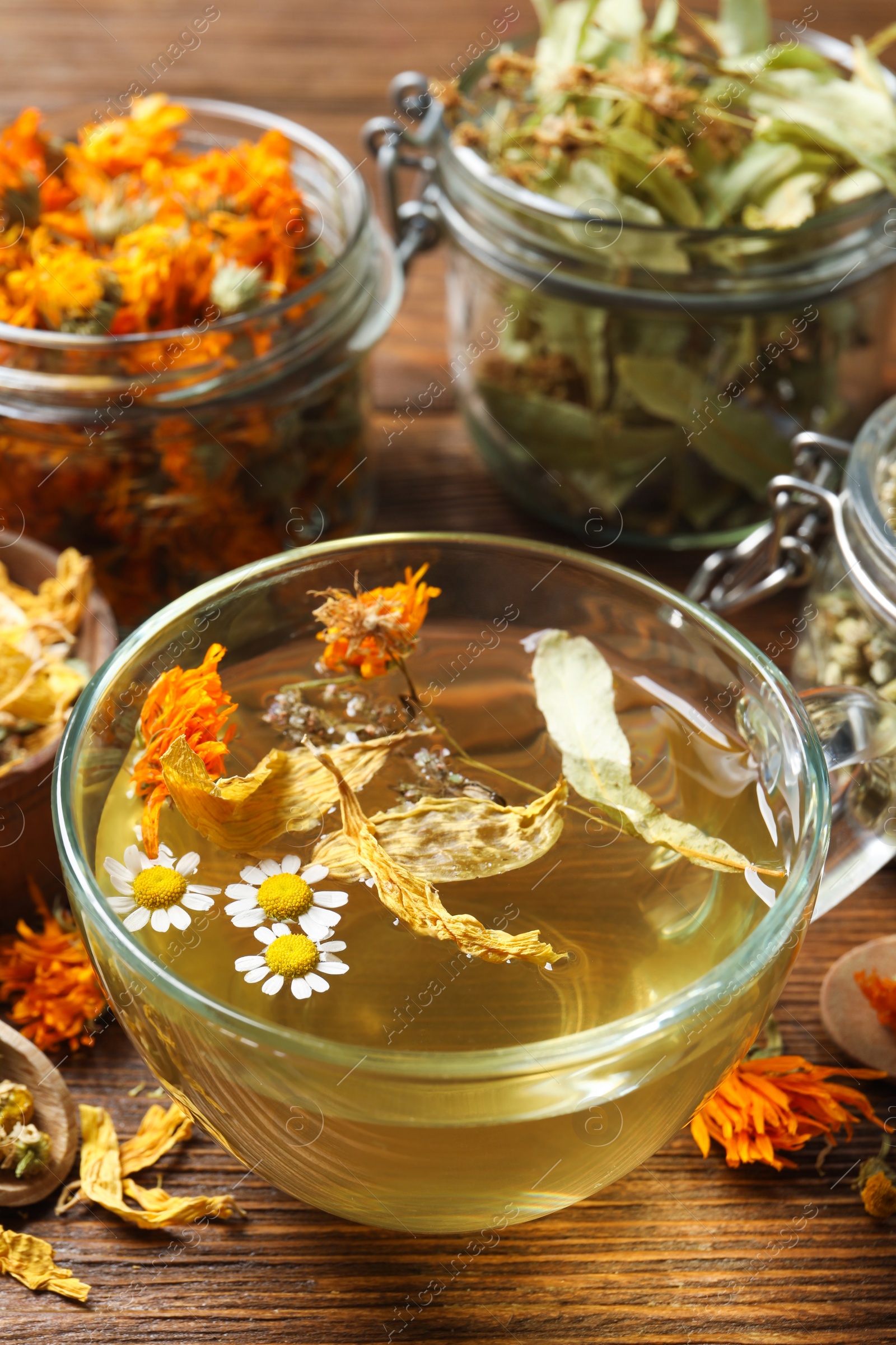 Photo of Freshly brewed tea and dried herbs on wooden table