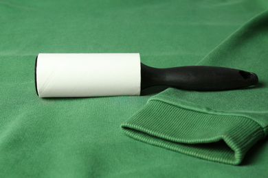 Photo of New lint roller with black handle on green sweatshirt
