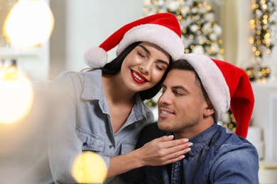 Happy couple in Santa hats at home. Christmas celebration