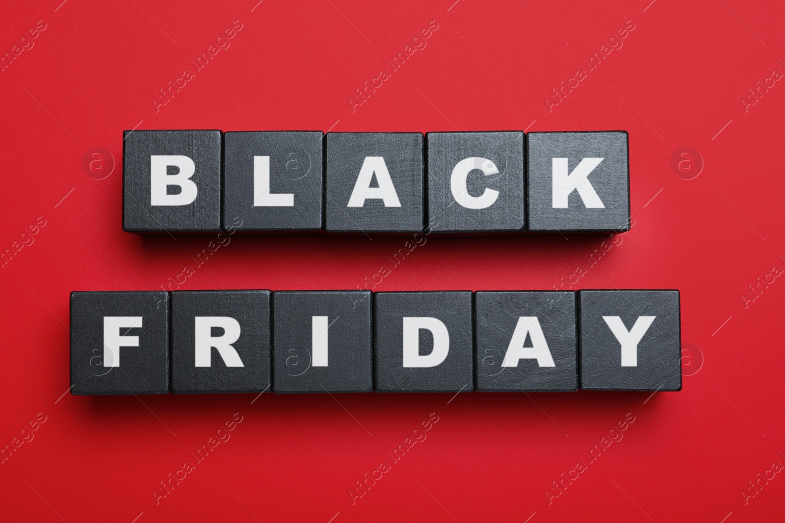 Photo of Wooden cubes with words Black Friday on red background, flat lay