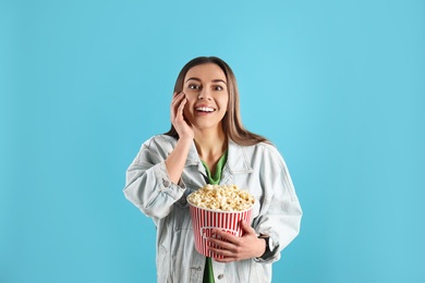 Photo of Emotional woman with tasty popcorn on color background