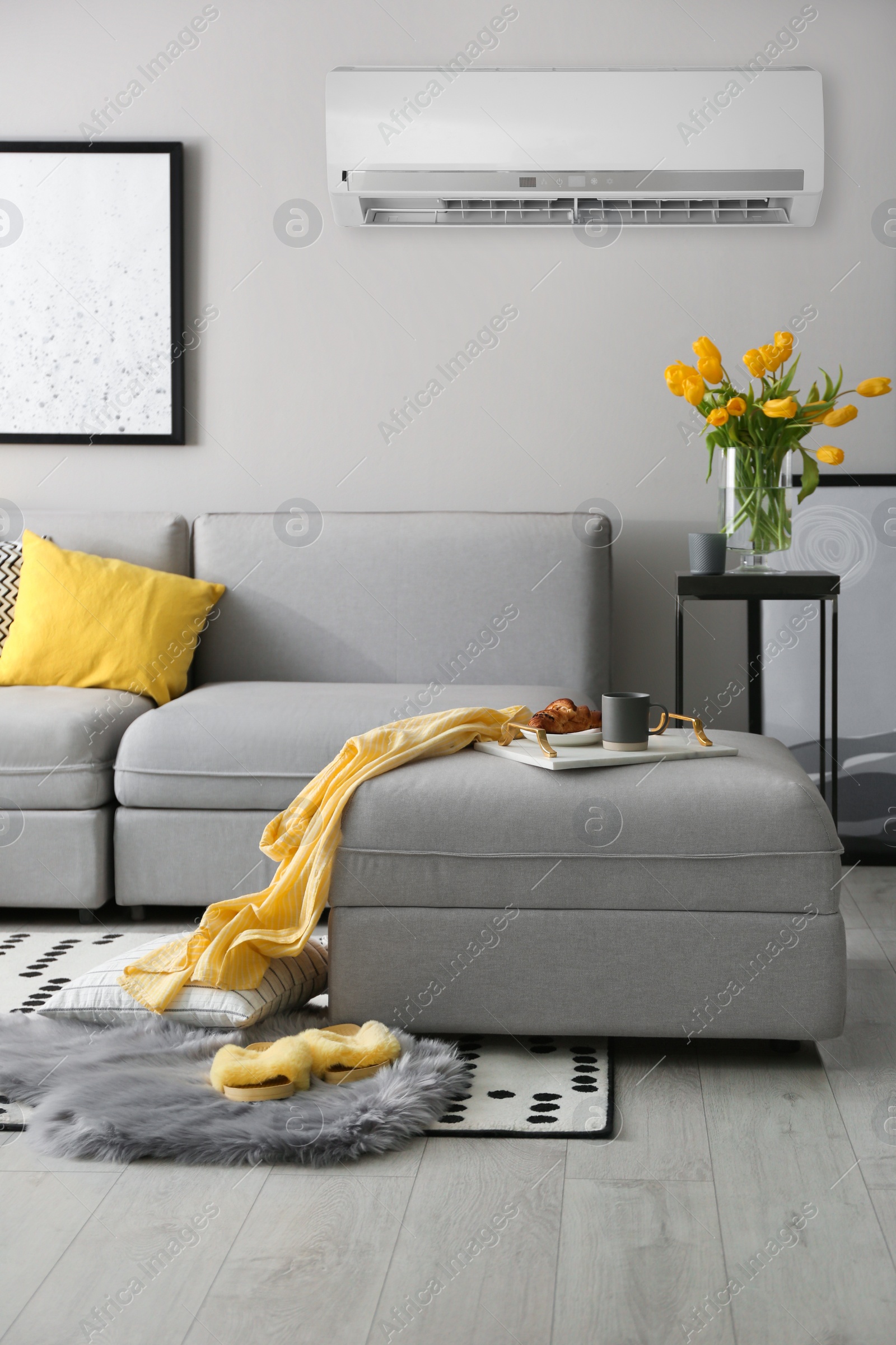 Image of Modern air conditioner on light grey wall in living room with stylish sofa