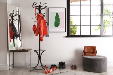 Photo of Modern hallway interior with clothes on hanger stand and mirror