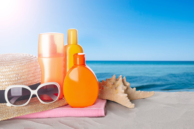 Image of Set of sun protection products and stylish accessories on sandy beach