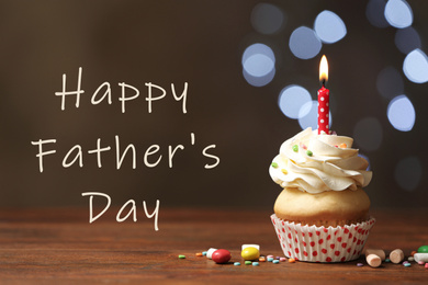 Image of Delicious cupcake with burning candle on wooden table and phrase HAPPY FATHER'S DAY against blurred lights