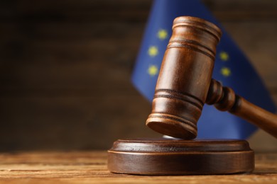 Photo of Judge's gavel and European Union flag on wooden table. Space for text