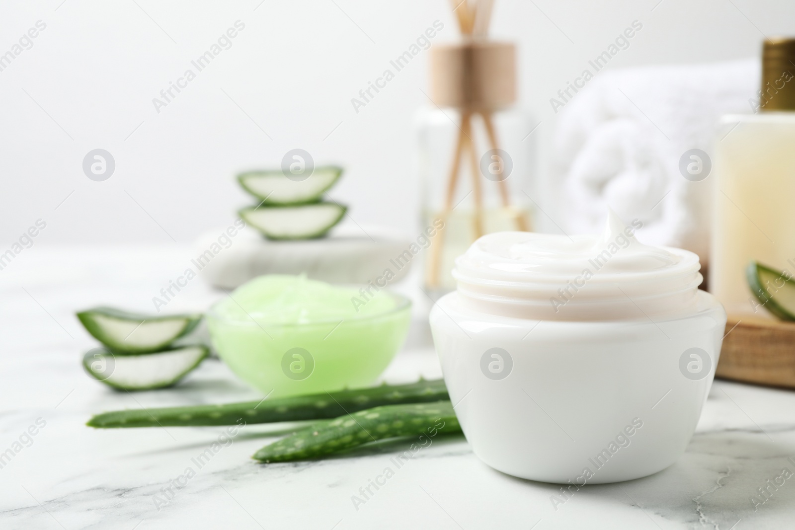 Photo of Open jar of cream and aloe on white marble table. Organic cosmetics