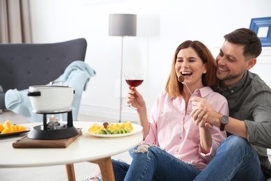 Happy couple enjoying fondue dinner at home