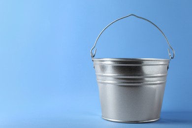 Photo of One shiny metal bucket on light blue background