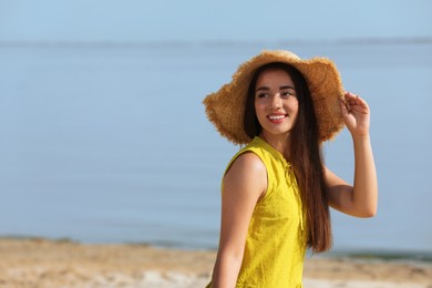 Beautiful young woman wearing straw hat on beach. Stylish headdress