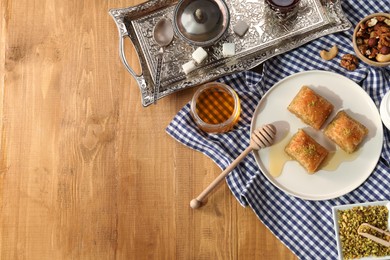 Photo of Delicious sweet baklava served on wooden table, flat lay. Space for text