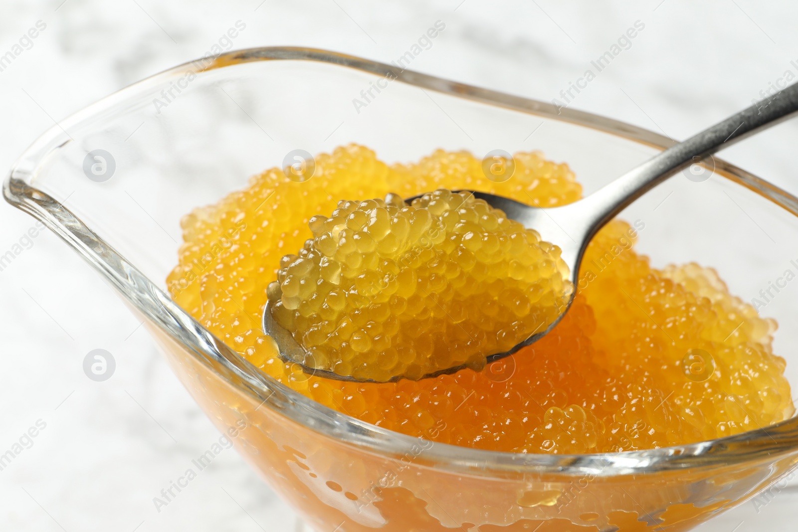 Photo of Fresh pike caviar in gravy boat and spoon on table, closeup