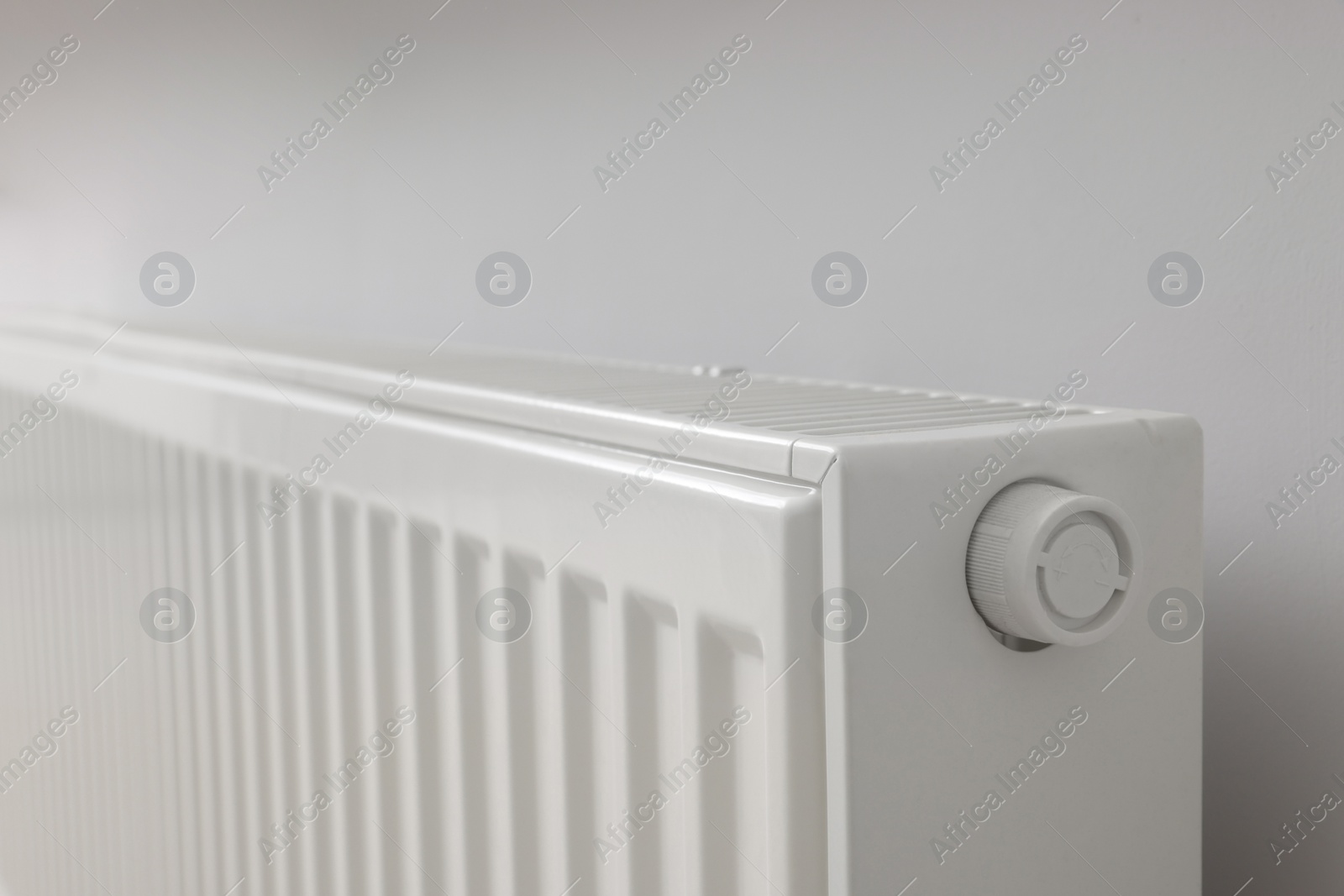 Photo of Modern radiator on white wall, closeup. Central heating system