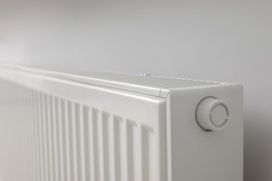 Photo of Modern radiator on white wall, closeup. Central heating system