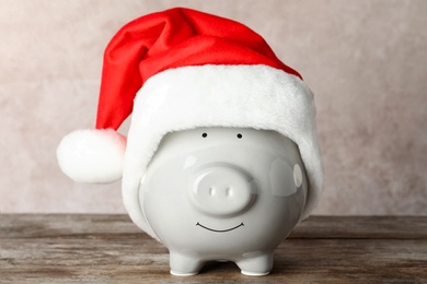 Cute piggy bank with Santa hat on table