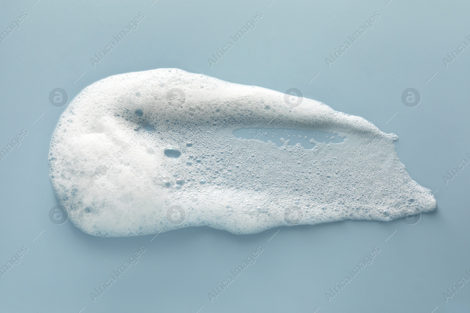 Photo of Smudge of white washing foam on color background, top view