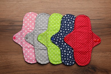 Many reusable cloth menstrual pads on wooden table, flat lay