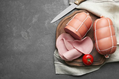 Board with tasty boiled sausages and tomato on grey textured table, flat lay. Space for text