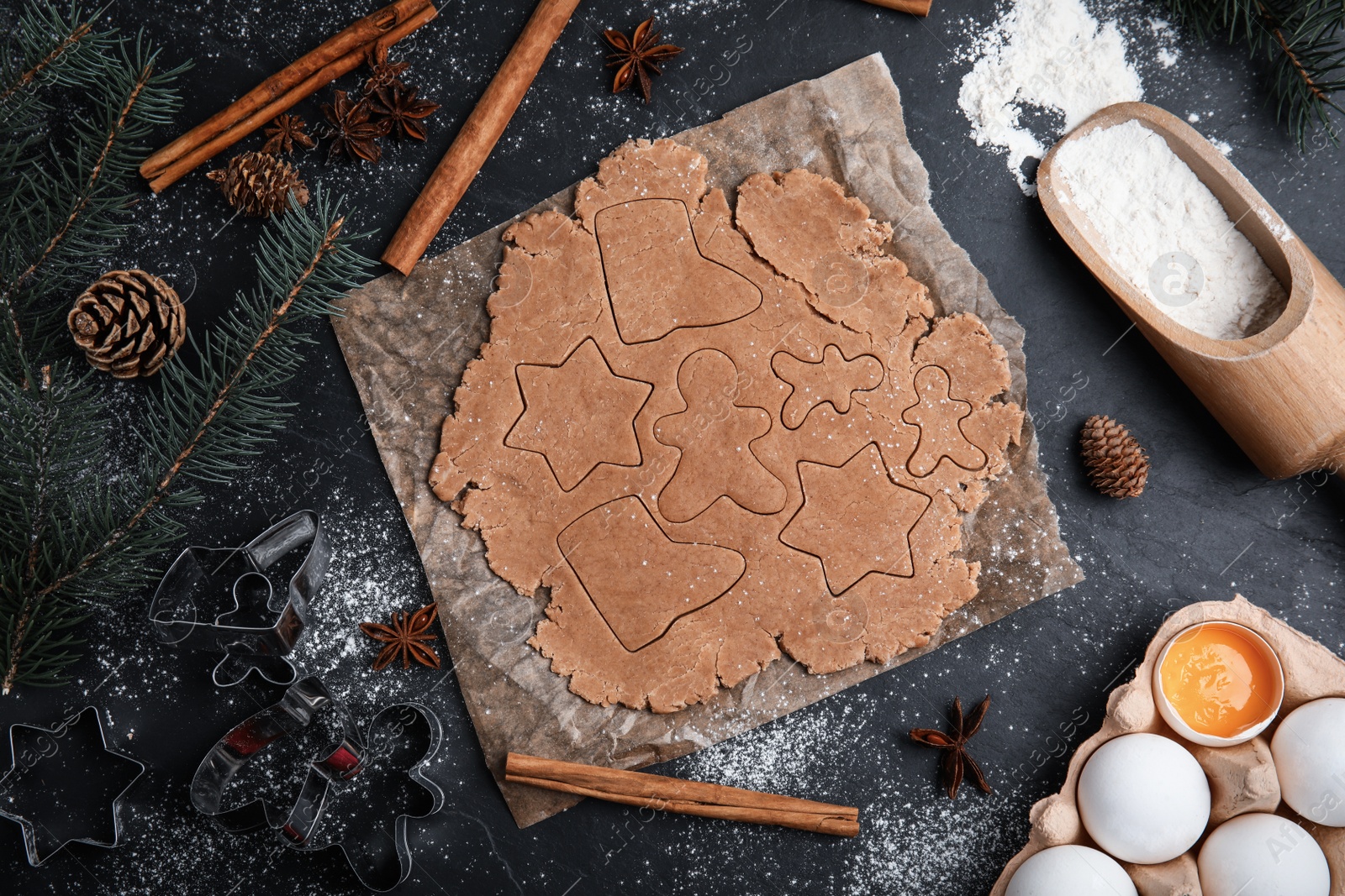 Photo of Making Christmas cookies. Flat lay composition with raw dough and ingredients on black table