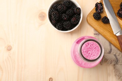 Photo of Delicious blackberry smoothie in glass bottle and fresh berries on wooden table, flat lay. Space for text