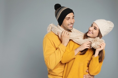 Photo of Happy young couple in warm clothes on grey background, space for text. Winter season